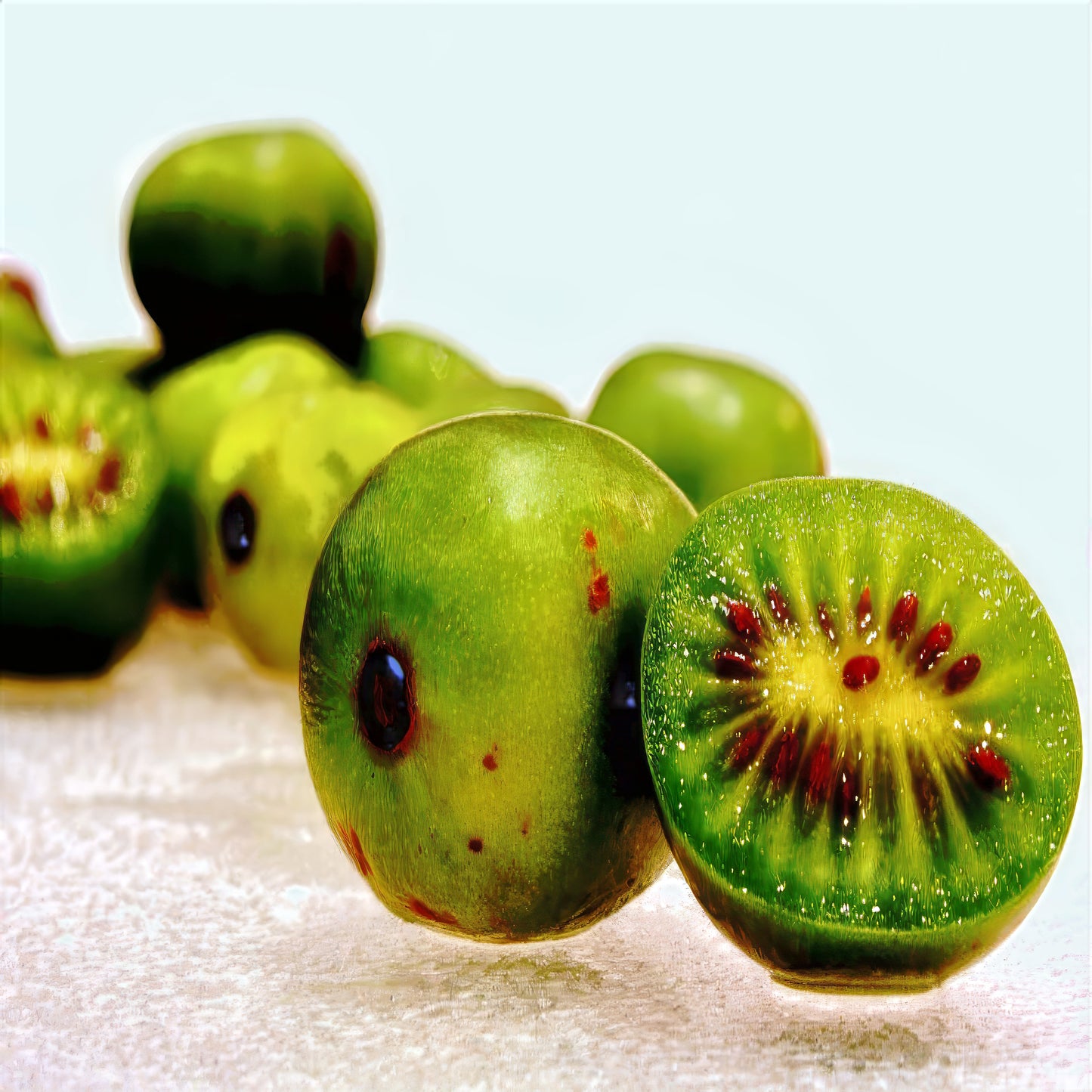 Close-up of skinless Issai kiwis with a focus on a sliced kiwi showing its green flesh and red seeds.