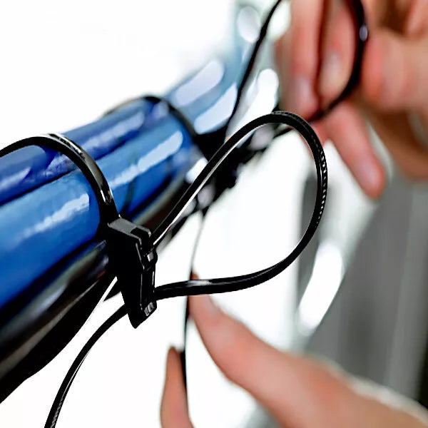 Person using a black cable tie to secure a blue cable against a blurred background