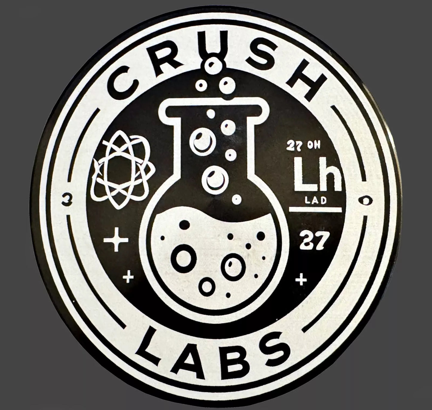 Logo of Crush Labs on grinder lid with a beaker and atom symbol on a dark background