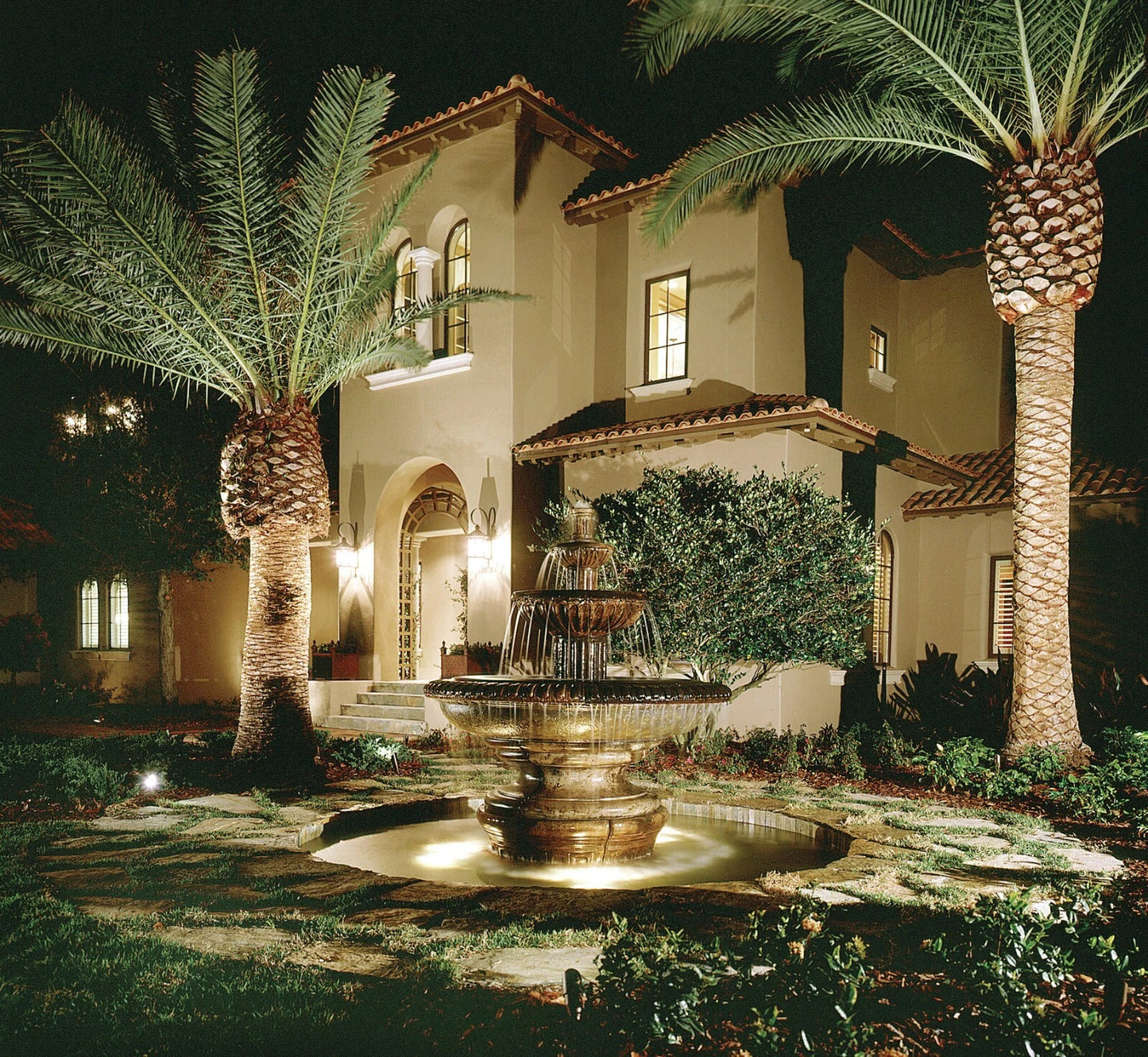 Luxurious house with a fountain and canary island date palm trees at night