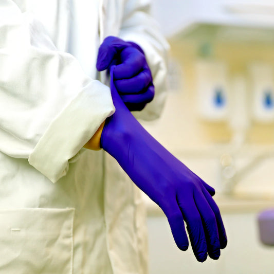 Person wearing a white lab coat and indigo nitrile exam gloves in a laboratory setting