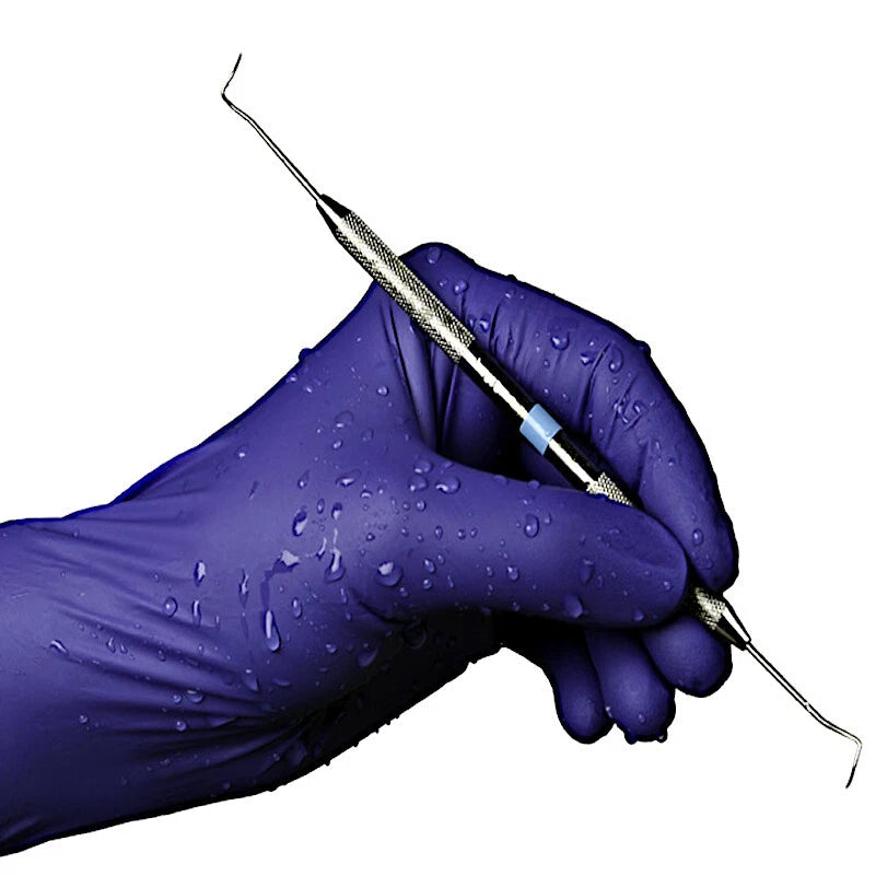 Hand wearing a indigo nitrile exam glove holding dental tool on a white background