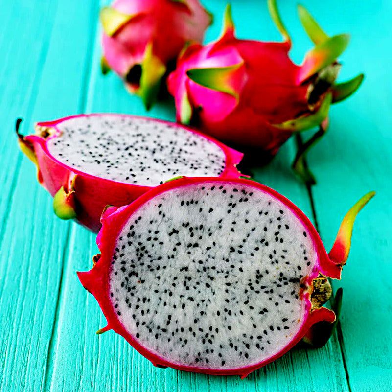 White dragon fruits with white flesh and black seeds lying on teal wood table. (Hylocereus undatus)