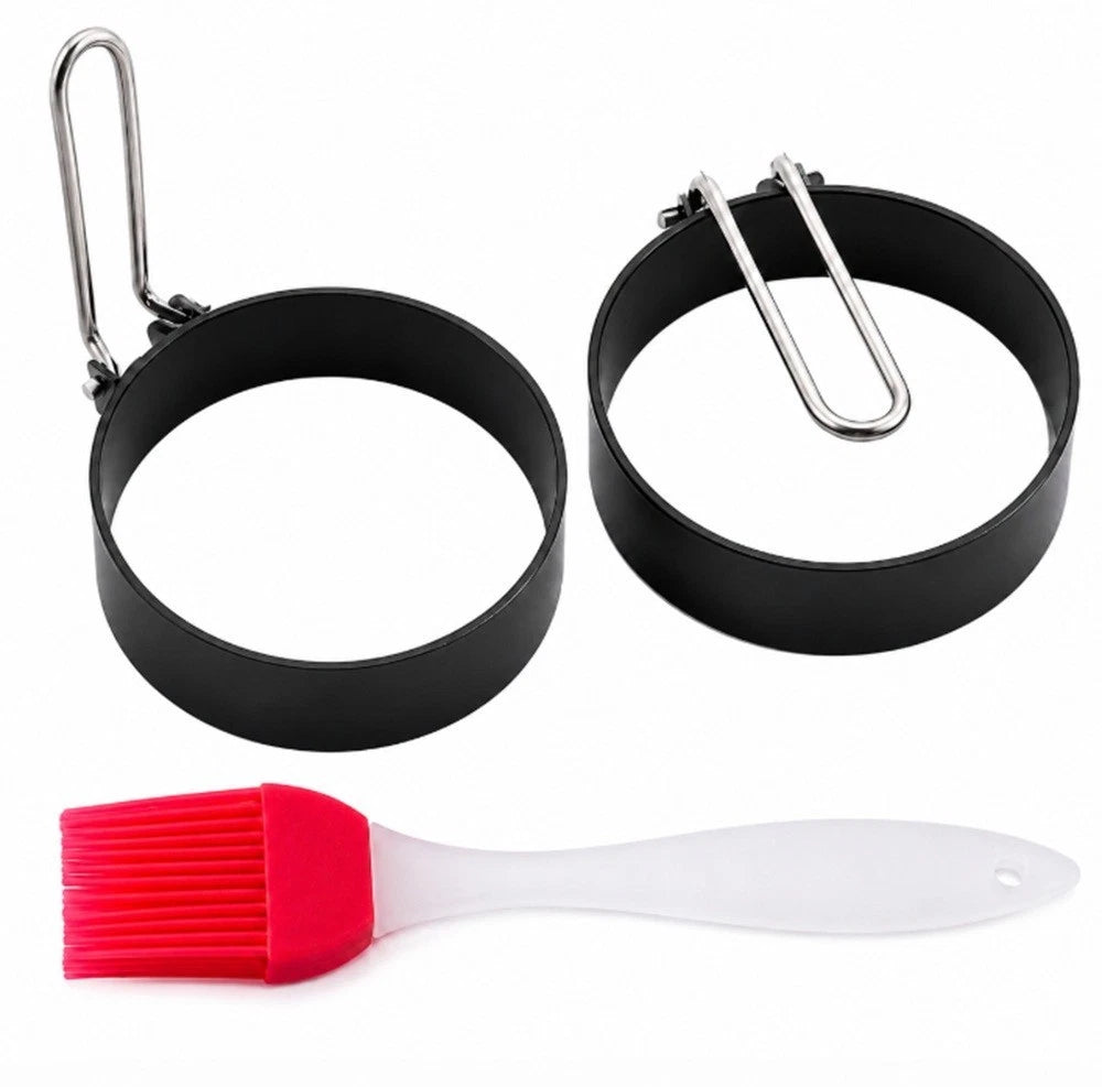 Two black circular non-stick metal egg ring molds with a red and white silicone brush on a white background