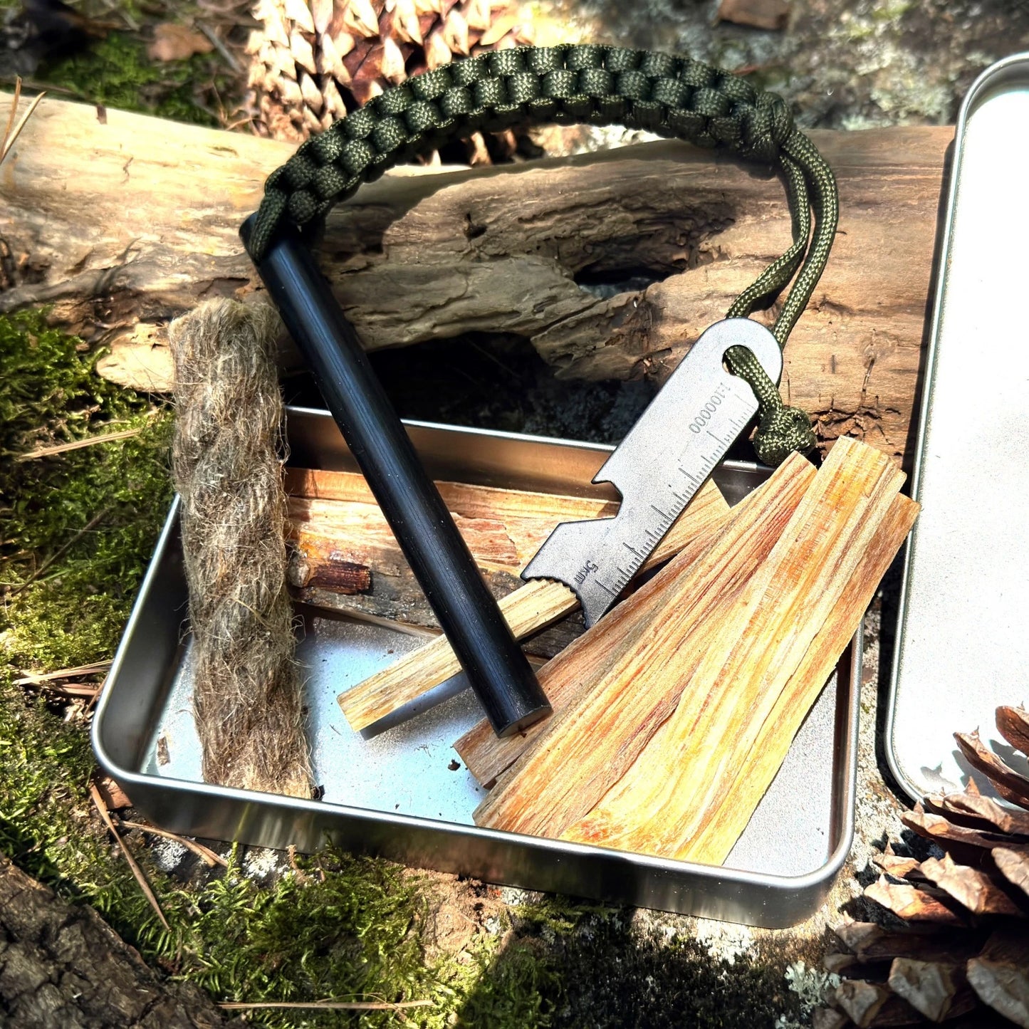 Survival kit with military size ferro rod fire starter, and fatwood, hemp rope kit in natural setting.