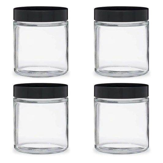 Four clear glass jars with black lids on a white background