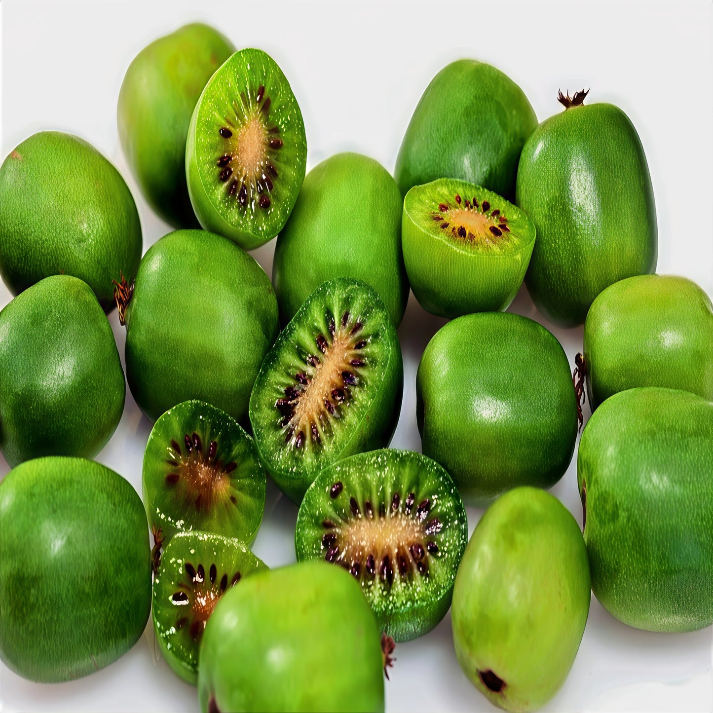 Green Issai hardy kiwis with some sliced open on a white background. Actinidia arguta