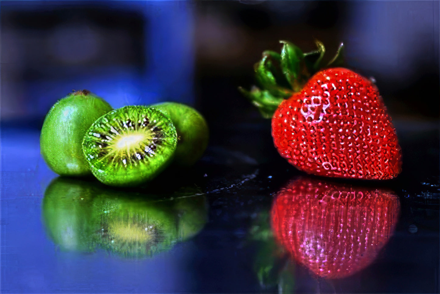Sliced Issai kiwi and a strawberry on a reflective surface with a blurred background