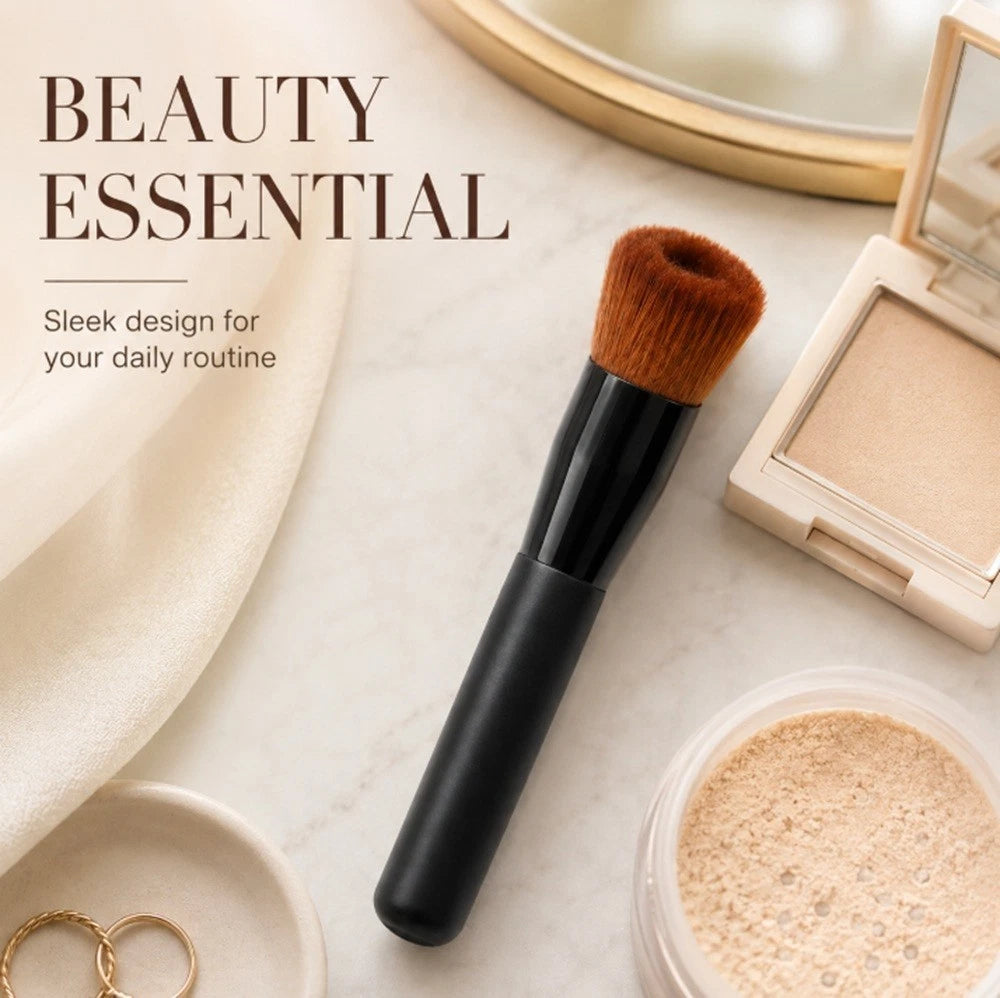 A black makeup brush with brown bristles is styled on a light marble surface with beauty products around it, including a compact powder, a loose powder container, a mirror, and small jewelry pieces. Text on the left reads 'BEAUTY ESSENTIAL' with smaller descriptive copy.