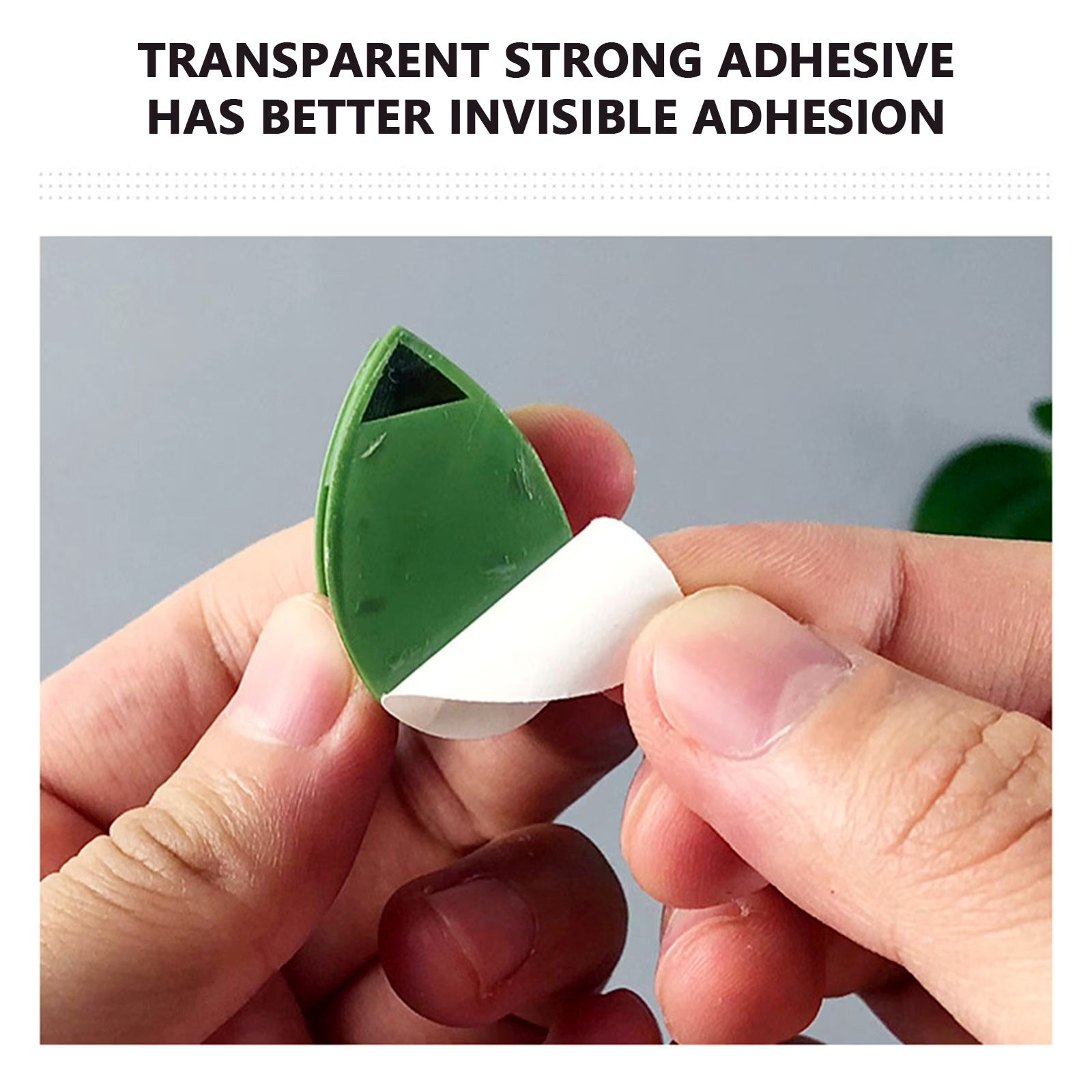 Green plant support clip with fingers pulling off paper showing transparent strong adhesive.