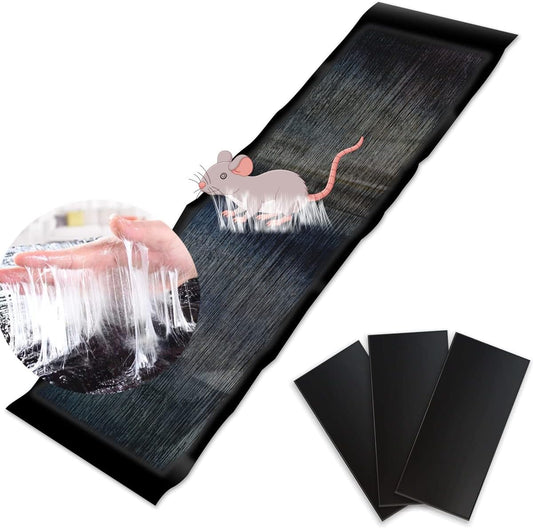 A large black glue trap laid out on a surface with an illustration of a mouse on it, alongside smaller glue traps folded and ready for use.