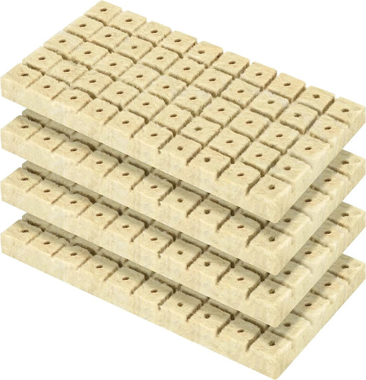Four stacked rectangular beige rockwool seed starting cube sheets, each covered with small square raised blocks with central holes, shown on a plain white background.