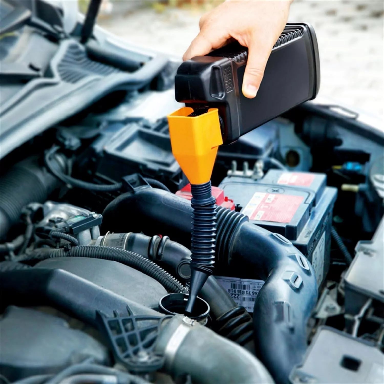 one hand snap funnel being used to pour oil into car