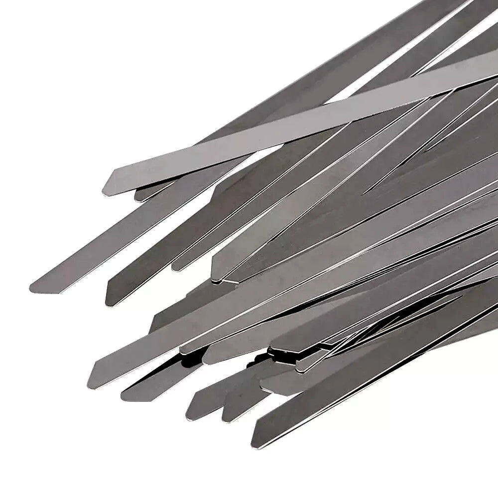 A pile of metallic silver stainless steel metal zip ties with angled tips, arranged diagonally on a plain white background.