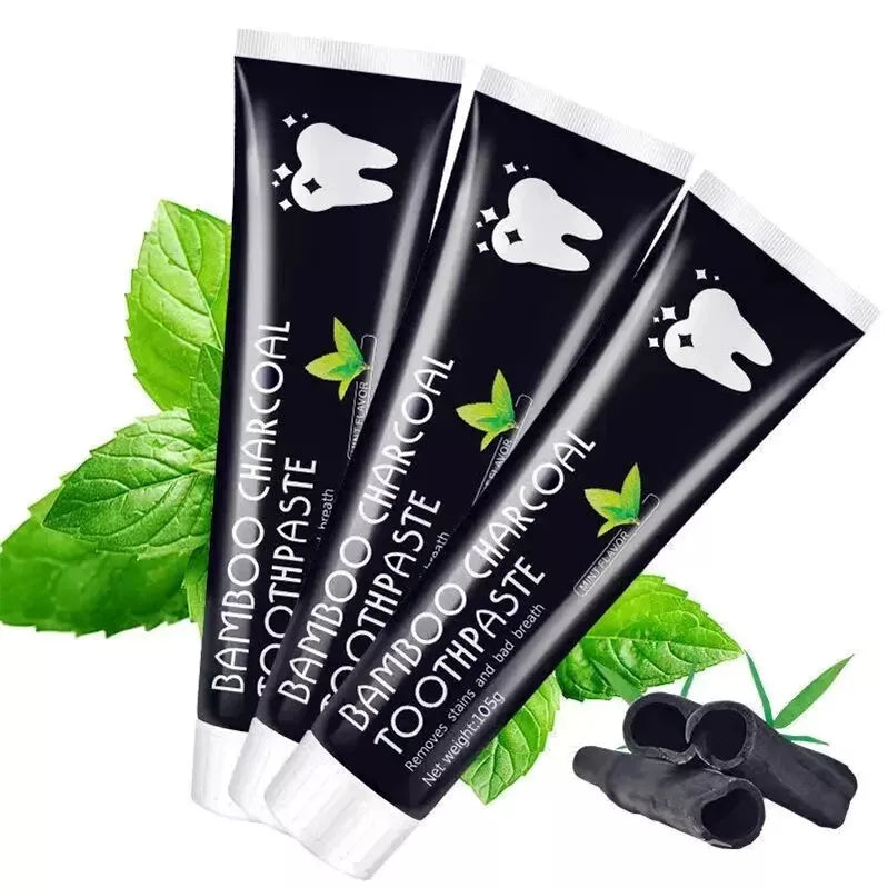 Three tubes of Bamboo Charcoal Toothpaste with green leaves on a white background