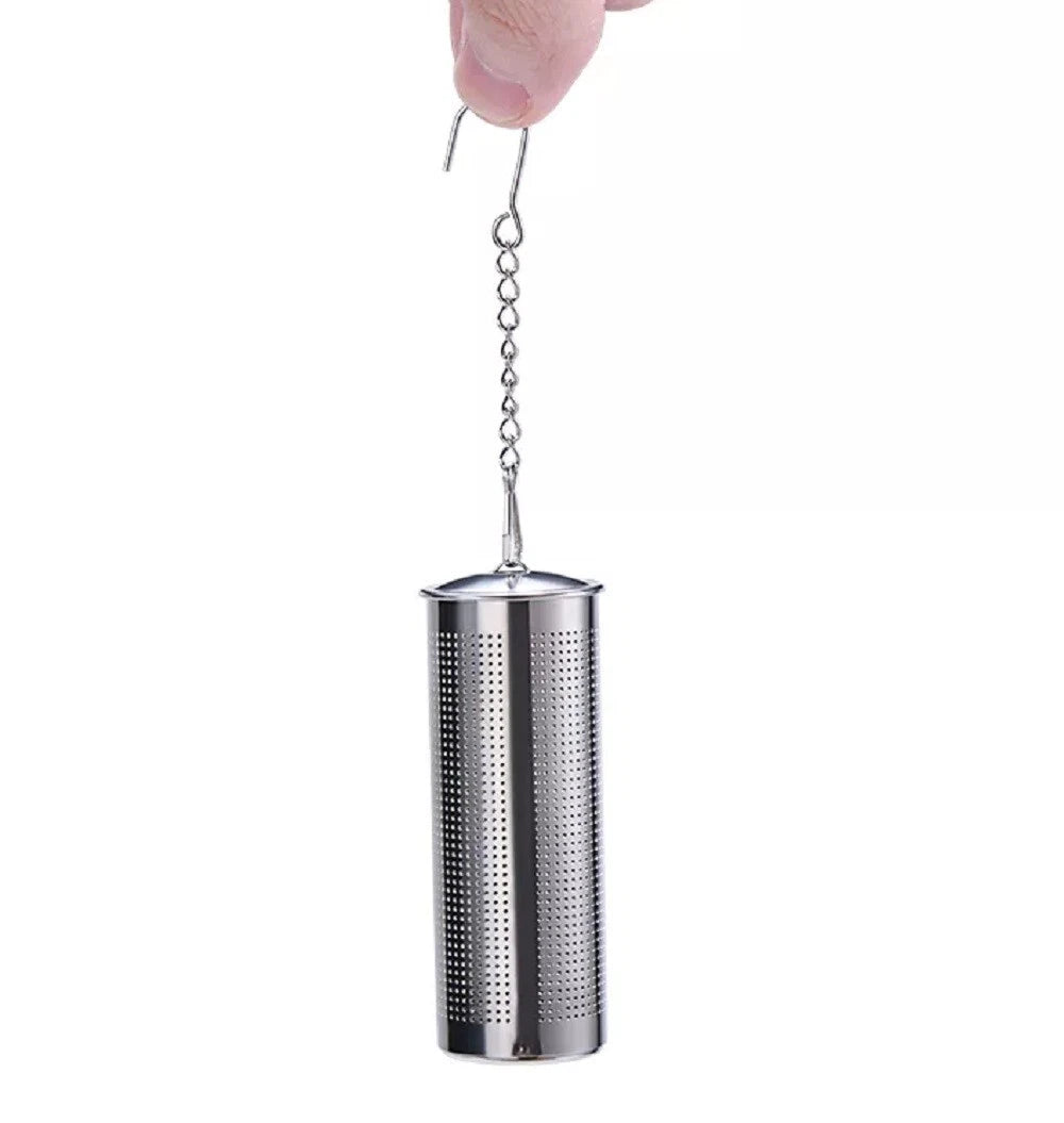 Metal tea infuser held by a hand on a white background